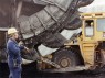 Mann vor Schaufelradbagger in der Braunhkohle.