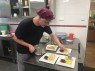 Ein junger Mann richtet Essen auf Tellern an.