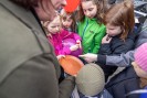 Nahaufnahme bei einer Kinder- und Familienführung: Fünf Kinder mit bunten Regenjacken stehen vor einer Frau, die ihnen einen Keramik-Teller zeigt. Die Kinder schauen neugierig auf den Keramik-Teller, während ein Kind auf den Teller zeigt.