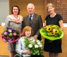 Drei Frauen und ein Mann. Die Frauen halten jerweils einen Blumenstrauß in der Hand.