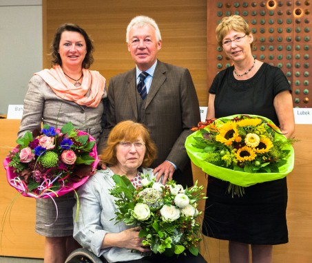 Ein Mann mit drei Frauen, die jeweils einen Blumenstrauß in der Hand halten.