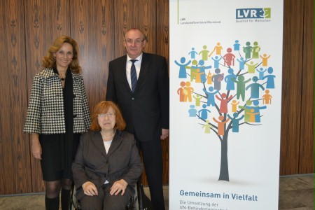 Drei Menschen neben einem Aufsteller