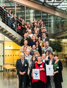 Viele Personen stehen auf einer Treppe. In der ersten Reihe hält eine Person ein Logo in der Hand: FLiP.