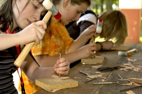 Mädchen, die mit Hammer Stück Holz bearbeiten