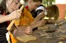 Mädchen schlägt mit einem Hammer einen Nagel in ein Stück Holz.