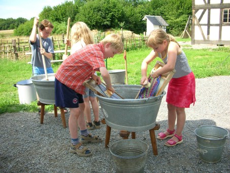 Kinder waschen wie früher mit Waschbrett