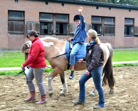 Junge auf Pferd. Zwei Frauen laufen nebenher.