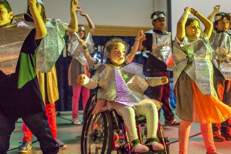 Kinder in grellbunten Kostümen tanzen.