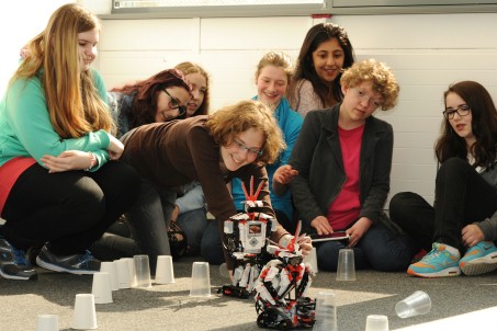 Junge Schülerinnen probieren einen Lego-Roboter aus.