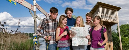 Gruppe von Menschen, die gemeinsach nach einem Weg in einer Karte suchen.