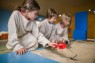 Bild zeigt Kinder bei einem Workshop mit Schaufel und Pinsel.