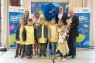 Gruppe Erwachsene und Kinder mit lebensgroßer Plüschfigur lachend