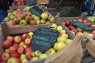 Äpfel in Holzkisten auf einem Marktstand. Auf Tafeln stehen die Namen der alten Apfelsorten.