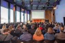 Ein Saal voller Menschen blickt auf eine Bühne