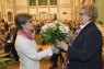 Bild zeigt eine Frau, die einer anderen Frau einen Blumenstrauß überreicht