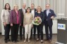 Vier Frauen und drei Männer mit einem Blumenstrauß