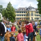 Eine Gruppe von Kindern und Erwachsenen bestaunen ein altes Spinnrad im Garten des Herrenhauses Cromford