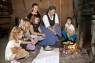 Mehrere Kinder und ein Erwachsener sitzen vor einer Feuerstelle und backen Reibekuchen.