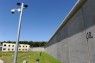 Grünstreifen vor hoher Mauer mit Klinikgebäude im Hintergrund