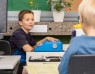 Zwei Jungen sitzen an einem Tisch. Einer von ihnen sitzt an einer Blindenschriftmaschine. Foto: Georg Krause/LVR