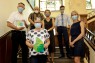 Sechs Personen auf einer Treppe mit Masken auf