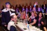 Man sieht mehrere Personen an einem langen Tisch sitzen. 