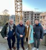 Drei Männer und eine Frau stehenvor einem Baukran