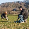 Man sieht eine Gruppe junger Menschen, die mit Rechen und Mistgabeln auf einer Wiese stehen. 