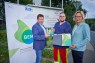 Man sieht zwei Männer und eine Frau vor einem Banner, auf dem "BEM" steht. Die beiden Männer halten einen Preis in der Hand, die Frau eine Urkunde.