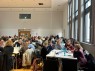 Viele Gruppen von Menschen sitzen an Tischen und tauschen sich aus.