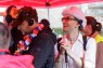 Zwei blinde Personen mit Headset h&ouml;ren der Blindenreportage beim CSD zu. Eine Person l&auml;chelt dabei und h&auml;lt ihren Blindenstock.