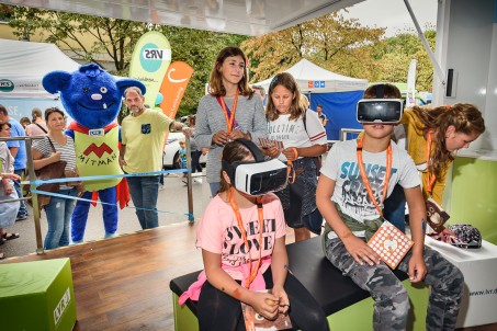 Zu sehen sind Kinder mit 3D-Brillen. Im Hintergrund steht das LVR-Maskottchen.