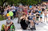 Viele Personen tanzen vor einer B&uuml;hne. Eine Person im Rollstuhl und eine Person, die sich niedergekniet hat, tanzen gemeinsam.