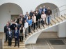 Auf dem Bild ist eine Gruppe Menschen zu sehen. Sie stehen auf einer Treppe. Sie gehören zur beratenden Arbeitsgruppe.