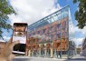 Eine Hand hält ein Smartphone hoch, auf dessen Bildshirm die Startseite des Mediaguides erscheint. Im Hintergrund sueht man die gläserne Fassade des Museums. 