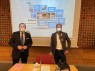 Frank Boss und Marc Janich vor einer Leinwand, auf der eine PowerPoint-Präsentation projiziert wird.