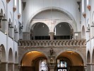 Blick in eine Kirche. Bögen prägen den Baustil, Lampen hängen von der Decke und verschiedene Heiligenstaturen sind an den Wänden auf Sockeln platziert. Über der Tür befindet sich eine Empore.