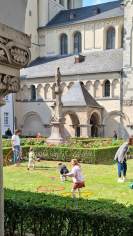 Kinder spielen mit Hula Hoop Reifen auf einer Wiese vor einer Kirche. 