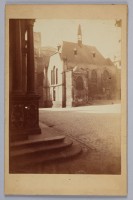 Gelbliche Fotografie, auf der ein Gebäude zu sehen ist. Es handelt sich um eine historische Aufnahme des Rathausplatzes mit Ratskapelle.