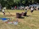 Foto: Wiese mit Körben und Spielzeug, im Hintergrund Menschen