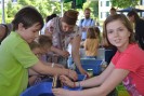 Foto: Bastelnde Kinder sitzen am Tisch und schauen in die Kamera