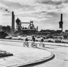Schwarz-Weiss-Foto: Fahrradfahrende Kinder in einer Industriekulisse
