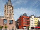 Ein signalrotes Haus am Alter Markt in Köln. Links daneben das Rathaus mit dem historischen Rathausturm