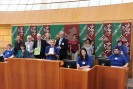 Auf dem Bild sitzen die Umweltassistenten mit ihren Urkunden im Plenumssaal des Landtags NRW und freuen sich.