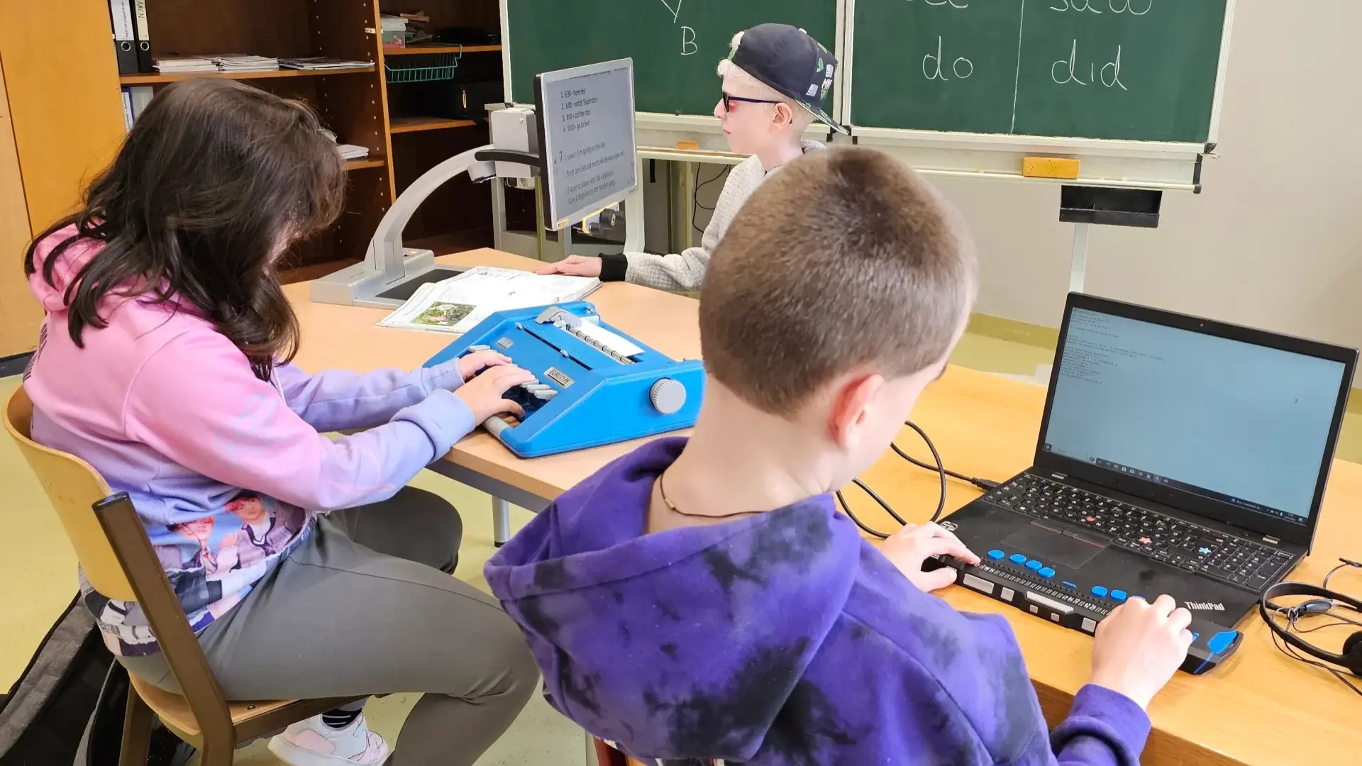 Schüler*innen sitzen im Klassenraum und bedienen Assistive Technologien 