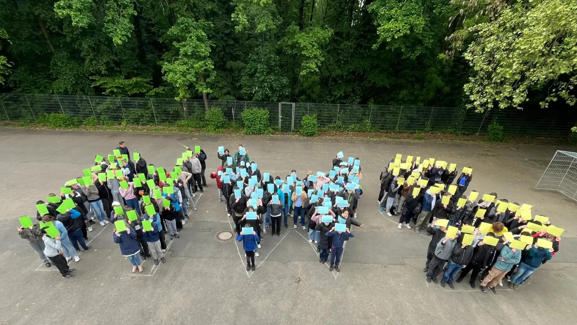 Schüler*innen formen auf Schulhof die Initialen der Schule "HWS"