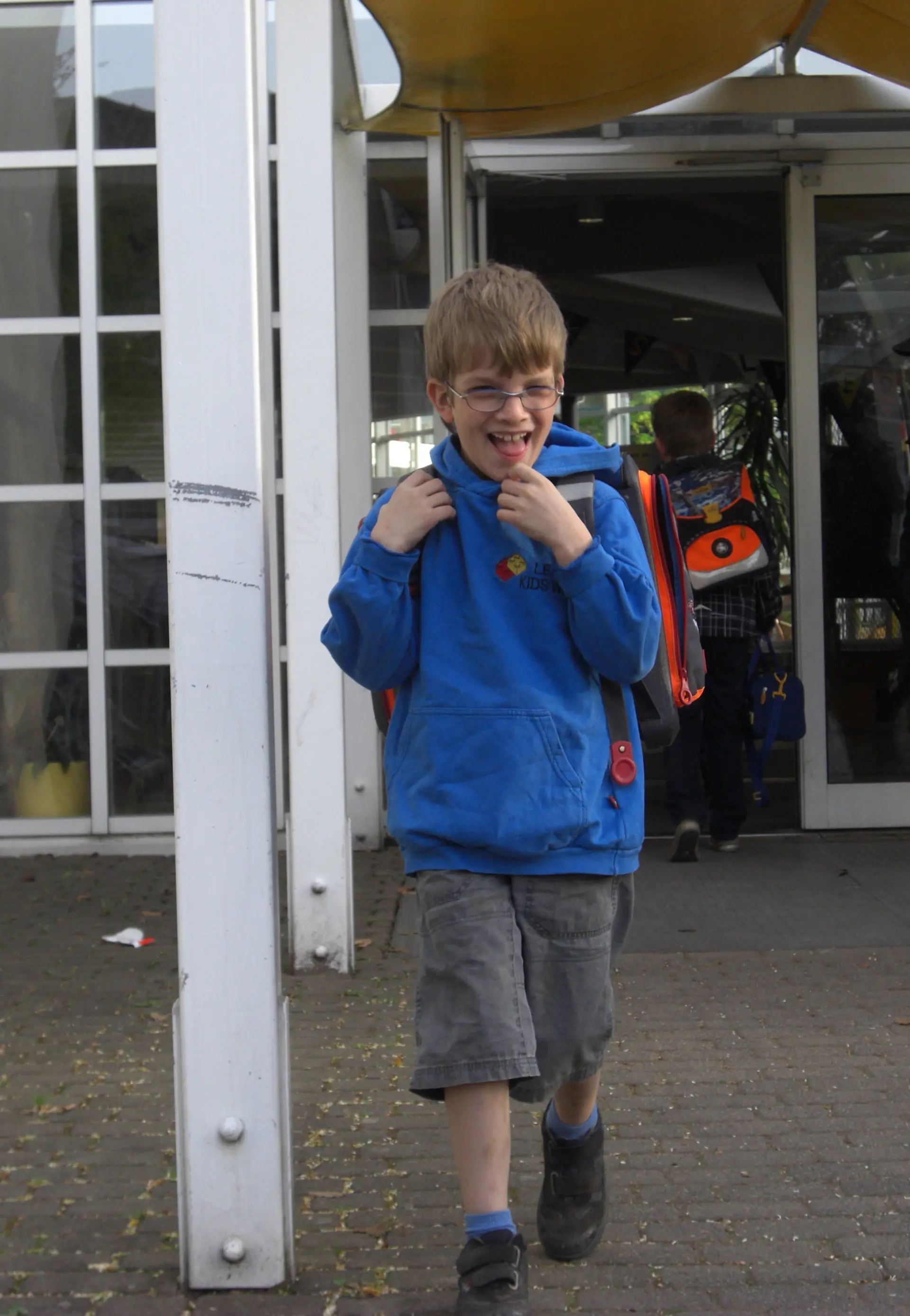 Inklusion trotz Sehbehinderung: Kind mit Brille geht allein aus dem Schulgebäude