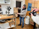 Man sieht einen Mann mit einem Holzstück, das in einer Klemme auf einem Tisch befestigt ist. Er steht im Labor für Dendrochronologie.