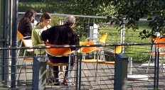 Drei Personen sitzen auf einer Terrasse im Sonnenschein