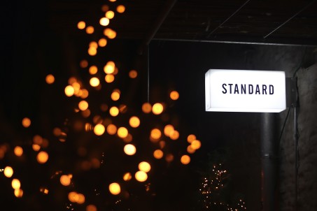 Eine Leuchtreklame mit dem Schriftzug "Standard" darauf. Dunkler Hintergrund und punktartige Lichteffekte.